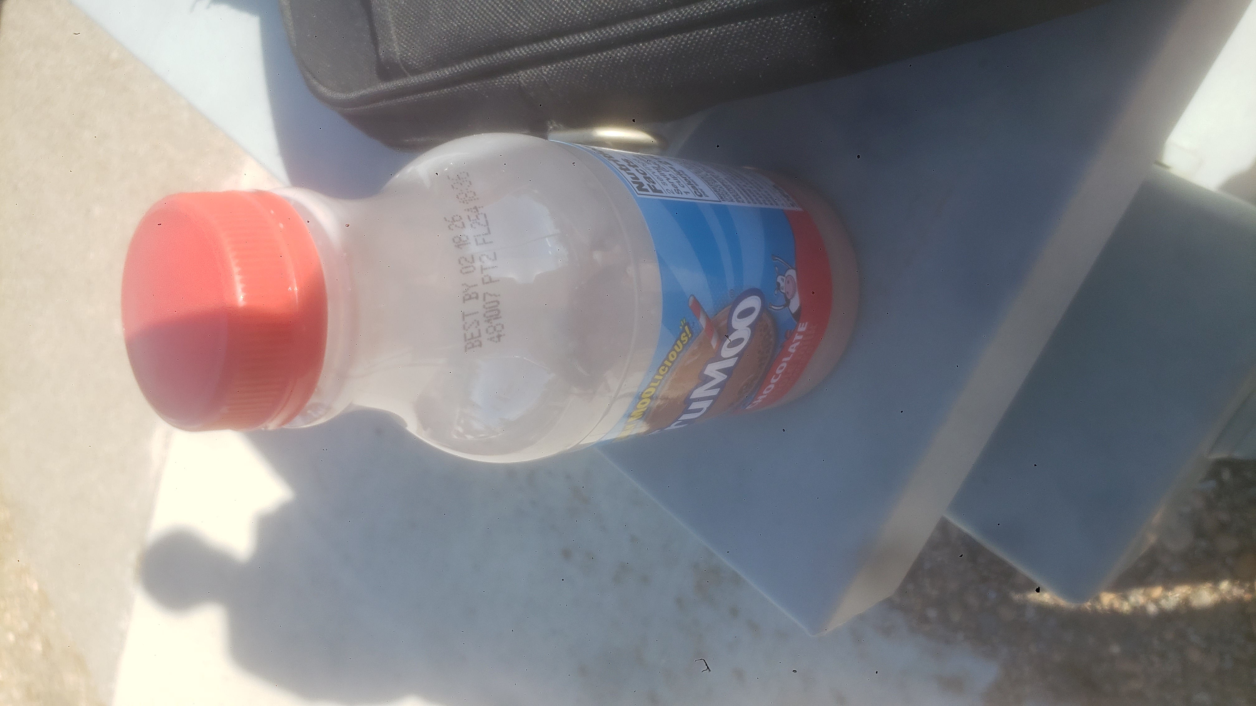 Bottle of chocolate milk next to laptop bag.